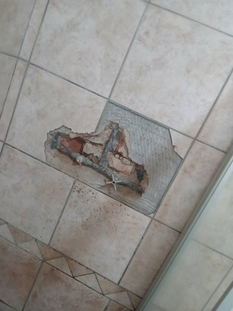 Floor tiles opened at one small point to reach a hidden leaking water pipe
