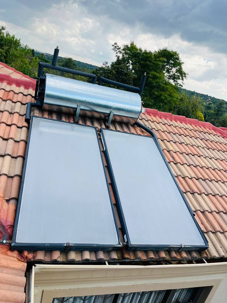 Flat-plate solar geyser with collector panels installed on a tiled roof