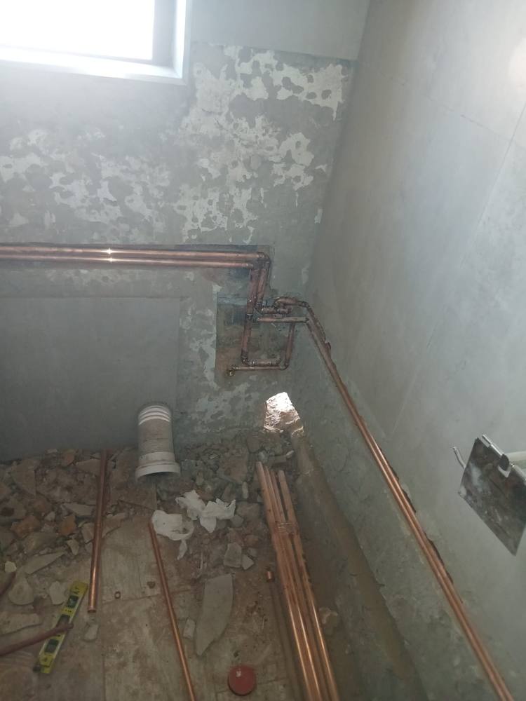 Copper hot and cold first-fix pipework chased into a bathroom wall
